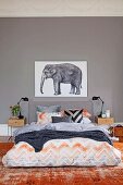 Interesting colour scheme in shades of grey and faded brick red; double bed with illustration of elephant above headboard