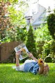 Frau liest eine Zeitschrift auf der Wiese im Garten