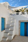 Blue door and lattice window in North-African courtyard with masonry samba staircase leading to roof terrace