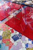 Transparent plastic chairs on red rugs and mosaic-style floor