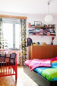 Colourful bedroom with double bed, cot & wall-mounted shelves