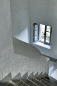 Offenes Fenster in weißem Treppenhaus mit grauen Stufen