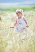 Blonde little girl walking through tall grass