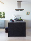 Free-standing, granite kitchen island below extractor hood in minimalist interior