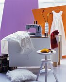 Sewing machine, sewing utensils & clothing on modern workbench & swivel stool