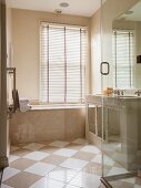 Elegant bathroom with marble clad tub and diagonal tile pattern on floor