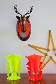 Mounted deer's head with safety-orange strips, star made from folding ruler and neon goblets