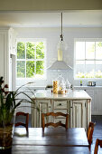 White, lacquer country kitchen with vintage look kitchen cabinets; natural wood dining area in the foreground