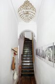 Kronleuchter an Decke in schmalem Gang mit Photogalerie an Wand vor Rundbogen und Treppenaufgang einer herrschaftlichen Wohnung