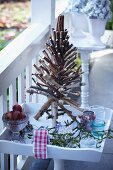 Weihnachtsdeko auf einem Terrassentischchen: Christbaum aus Zweigen, Äpfel, Mistelzweige