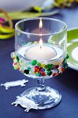 Floating candle in glass decorated with confetti & lucky pig charms