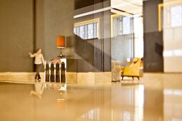 Spacious minimalist hotel foyer with glossy floor and woman in background