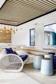 Überdachte Terrasse mit maritimem Sessel aus weiss lackierten Holzstäben