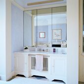 White washstand and triple mirror in niche in traditional bathroom with pastel-painted walls