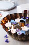 Bundt tin filled with water, floating candles & viola flowers