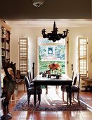 Dining table in front of open terrace doors with interior, folding shutters; stylised, painted, wooden bird statue