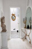 Gilt accents and antique accessories in hallway with view into bathroom through open door