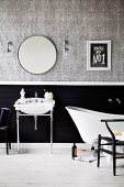 Washstand with chrome frame and bathtub in front of partially black-tinted wall, papered above with a gray pattern