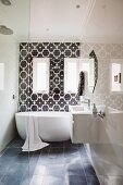 Modern bathroom with floating washstand on glossy wall and free-standing bathtub against wall with black and white tiled wall with Oriental pattern
