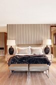 Doppelbett mit Felldecke und ledergepolsterten Kleiderbänken im eleganten Schlafzimmer mit Bad Ensuite