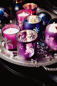 Glass candle holders and Christmas ornaments on a silver tray