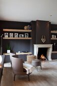 Classic modern armchairs with grey leather upholstery in front of open fireplace in black-painted wall in elegant living room