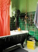 Green bathroom with freestanding, antique bathtub and fire engine red shower curtain with ruffles