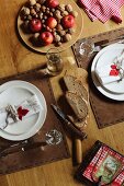 Festive place settings with decoratively stitched leather place mats; plate of apples and nuts
