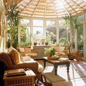 Light-flooded conservatory with wicker sofa set and traditional-style coffee table with turned wooden legs