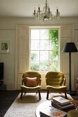 Zwei Vintage Sessel vor Sprossenfenster mit Innenläden und Stehleuchte in traditionellem elegantem Ambiente