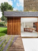 Blick von der Terrasse in modernen Wohnraum mit Küchentheke aus Edelholz und Barstühlen im Bauhausstil