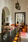 Moroccan lantern lamps above long dining table and seating area with large mirror in background