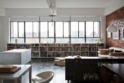 Open-plan kitchen area with sideboard in front of half-height bookcase below ribbon window in loft-style interior