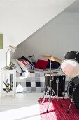 Bed with patchwork bedspread under sloping ceiling & drum kit in teenager's bedroom