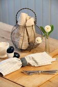 Breakfast in rustic ambiance - linen napkin and cutlery in front of wire basket on wooden table