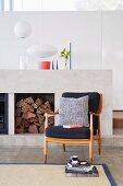 Modern fireplace in architect-designed house and comfortable reading chair with wooden arms
