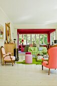View from seating area with Rococo armchairs, pink stools and modern, striped sofa into dining area in conservatory extension