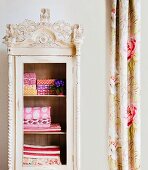 Colourful, patterned, folded fabrics in antique, vintage-style wardrobe