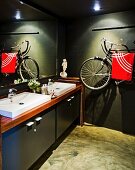 Dark-painted bathroom with modern washstand and bicycle hung on wall used as towel rack