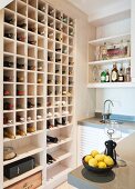 Modern kitchen with large wine rack in fitted shelving; bowl of lemons on counter