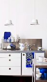 Two hand-crafted pendant lamps made from enamel bowls above kitchen sink with retro-style draining rack