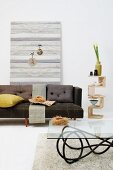Sofa, Glastisch und additives Beistellregal mit Naturdeko vor Bretterwand in Grautönen