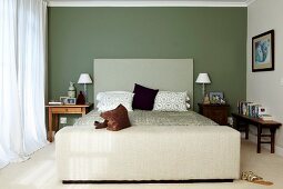Schlichtes Bett mit Kopfteil an grün getönter Wand in klassischem Schlafzimmer