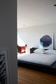 Black double bed with framed, modern artwork standing on headboard