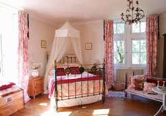 Messingbett mit luftigem Himmel zwischen Fenstern in der Ecke eines traditionellen Schlafzimmers