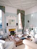Elegante hellgraue Polstermöbel um gepolstertem Couchtisch in traditionellem Wohnzimmer mit offenem Kamin
