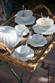 White china tea service in leaf design on wicker tray on metal stand