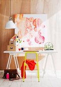 White desk and yellow chair below abstract watercolour on wall