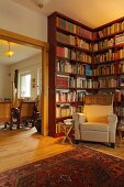 Library in village house with floor-to-ceiling bookcases and armchair (Eggelingen, East Frisia, Germany)