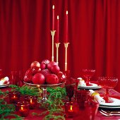 Festively set table with candlesticks in front of closed red curtain